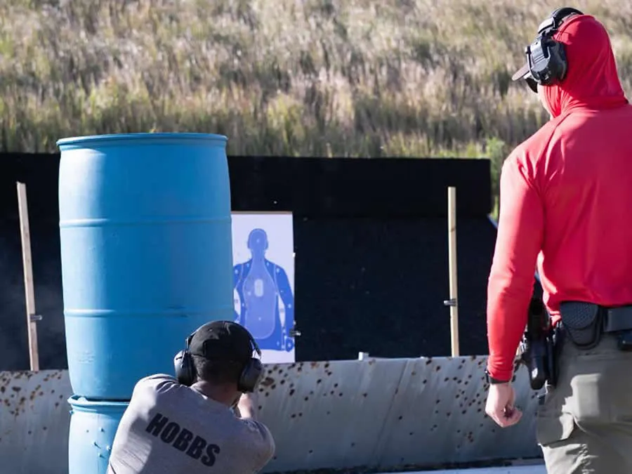 Instructor monitoring cadet shooting at outdoor training range