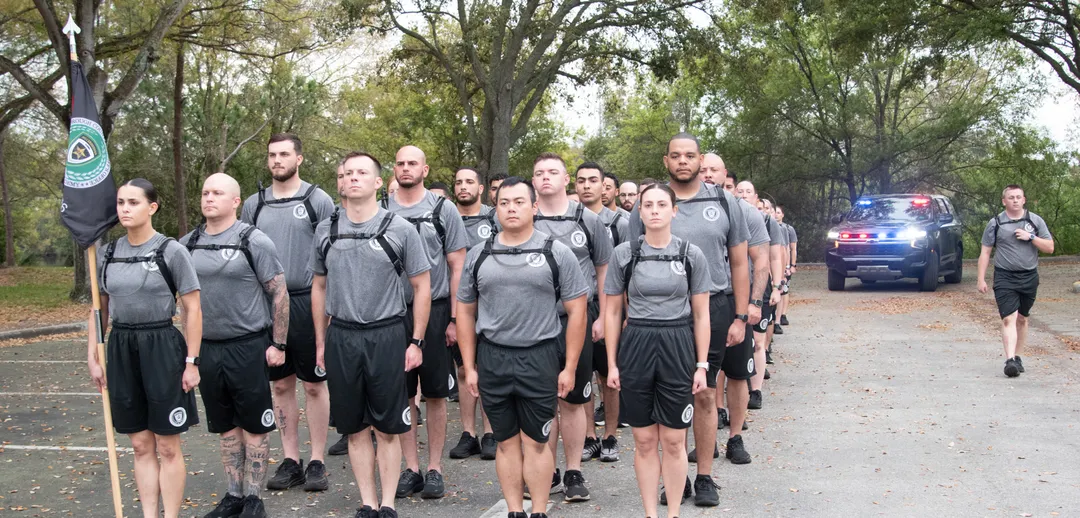 Group of cadets marching outdoors in formation during physical training.