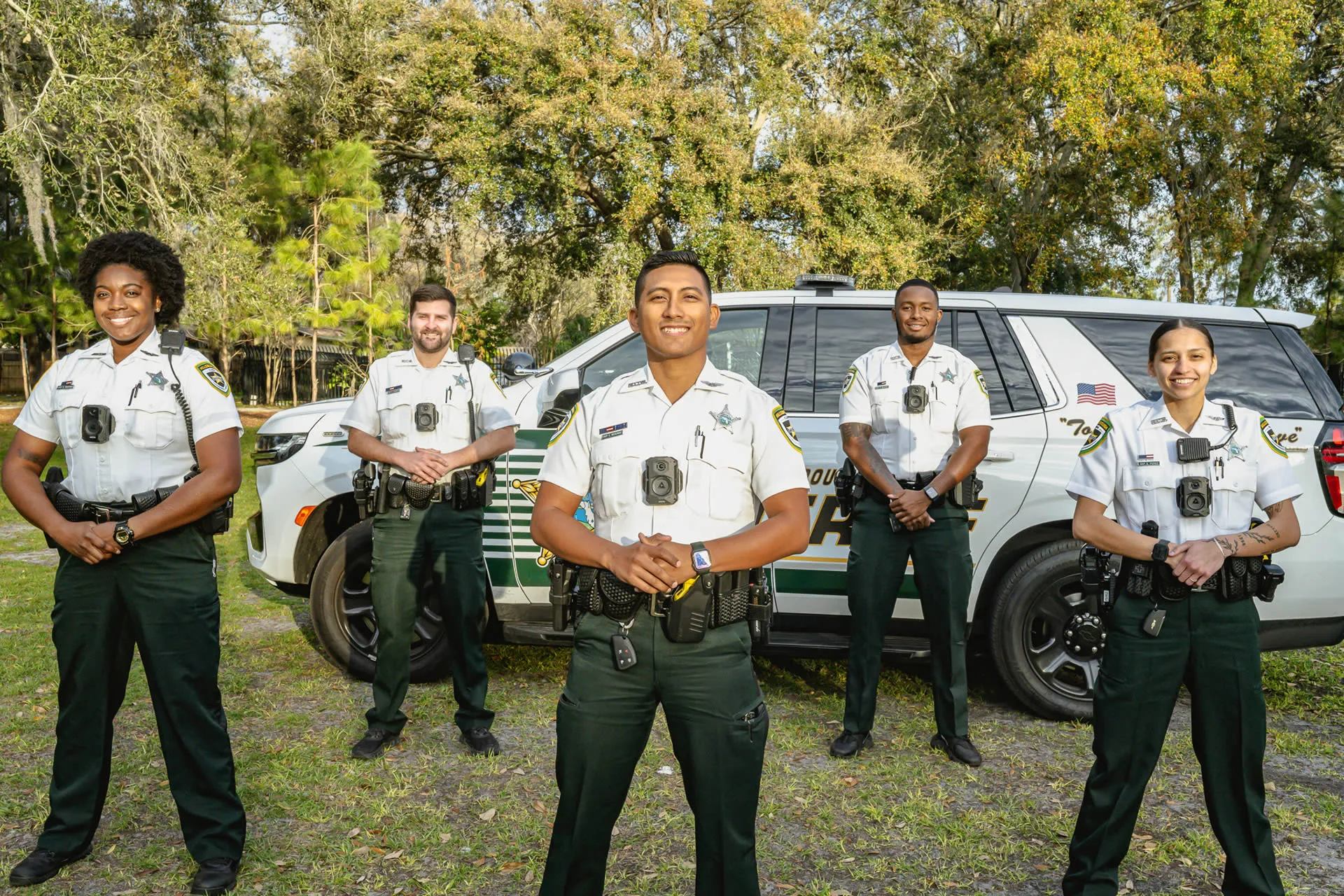 five deputies in uniform standing proudly in front of patrol vehicle